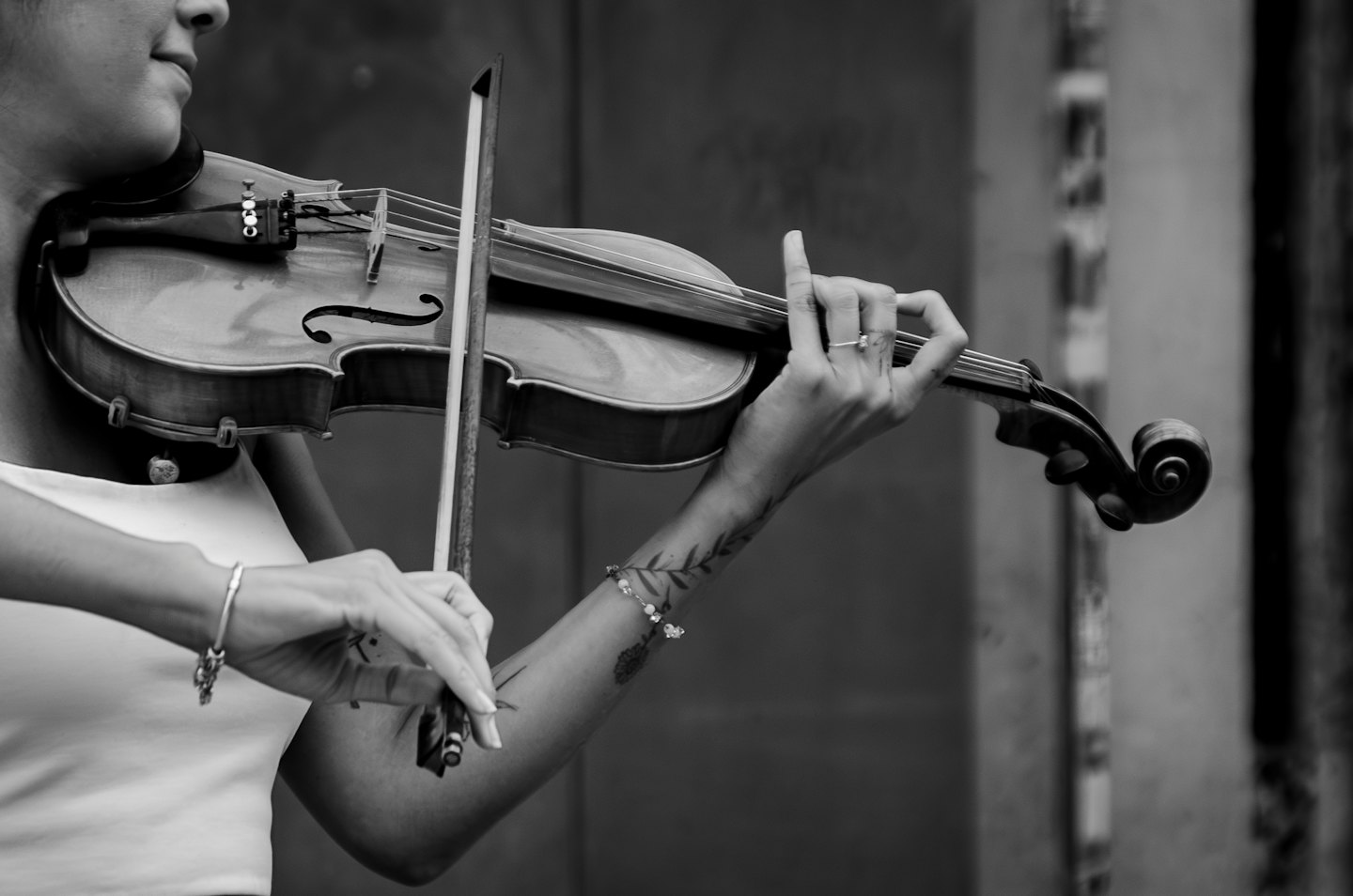 Musician playing a violin with a tattoo on their arm.