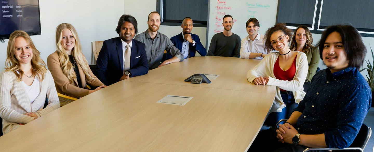 Diverse team smiling around a conference table in a modern office.