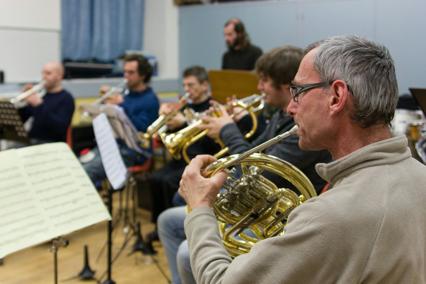 A musician plays a French horn during a brass ensemble rehearsal.
